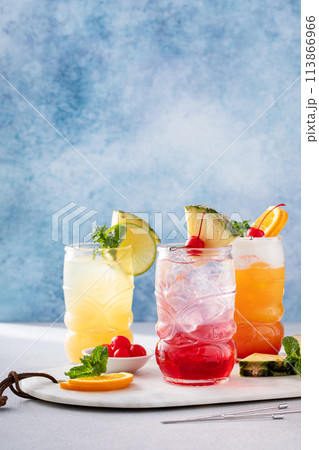 Variety of tropical tiki cocktails with cold foam, garnished with orange slices, cherry and mint 113866966