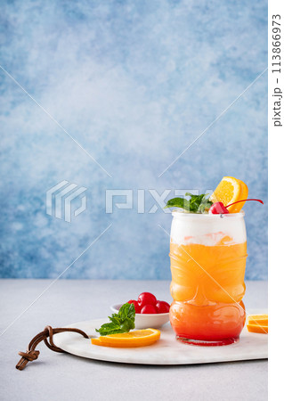 Tropical tiki cocktail with cold foam, garnished with orange slices, cherry and mint Tropical tiki cocktail with cold foam, garnished with orange slices, cherry and mint 113866973