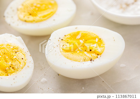 Boiled eggs peeled and cut in half with salt and pepper 113867011