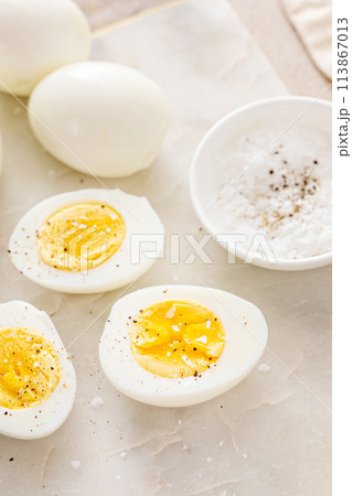 Boiled eggs peeled and cut in half with salt and pepper 113867013
