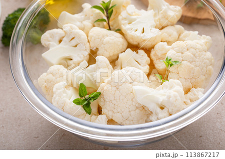 Raw cauliflower florets in a glass bowl, ready to roast with spices and olive oil 113867217