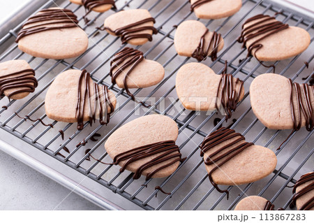 Heart shaped cookies with strawberry flavor, drizzled with dark chocolate 113867283