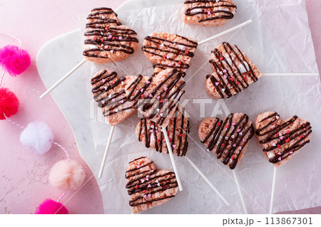 Pink heart shaped rice krispie treats drizzled with dark chocolate on a marble board 113867301