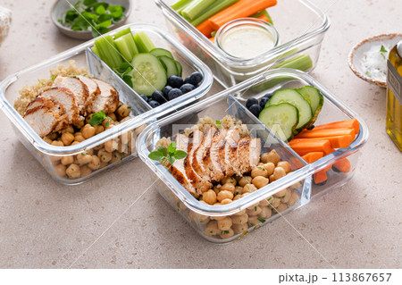 High protein healthy lunch meal prep in containers with chicken, quinoa, herbed chickpeas, vegetables and eggs 113867657