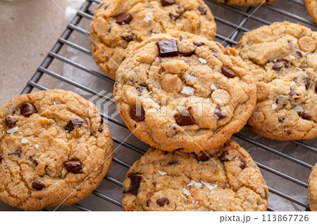 Chocolate chip cookies on a cooling rack with flaky salt served with milk 113867726