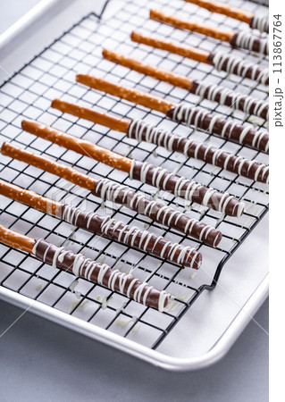 Chocolate dipped pretzel rods on a cooling rack 113867764