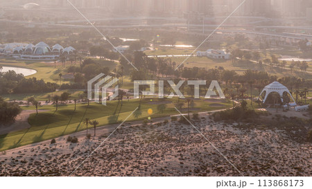 Golf course and Dubai Marina skyscrapers during sunset timelapse, Dubai, United Arab Emirates Golf course and Dubai Marina skyscrapers during sunset timelapse, Dubai, United Arab Emirates 113868173