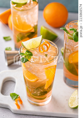 Orange and lime mojito cocktail in tall glasses with lime and mint Orange and lime mojito cocktail in tall glasses with lime and mint 113868574