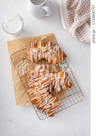 Bear claw pastry on a cooling rack with glaze and almonds 113868747