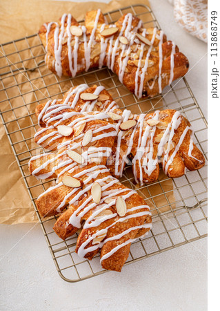 Bear claw pastry on a cooling rack with glaze and almonds 113868749