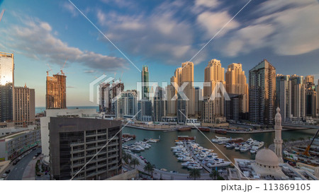 Yachts in Dubai Marina flanked by the Al Rahim Mosque and residential towers and skyscrapers aerial timelapse. 113869105