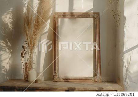 A rectangular picture frame on a hardwood table next to a dried flower vase, mockup 113869201