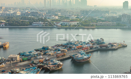 Dubai creek landscape timelapse with boats and ship in port and modern buildings in the background during sunset 113869765