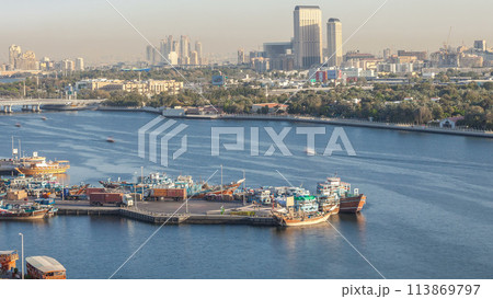 Dubai creek landscape timelapse with boats and ship in port and modern buildings in the background during sunset 113869797
