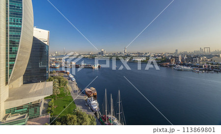 Dubai creek landscape timelapse with boats and ship in port and modern buildings in the background during sunset 113869801