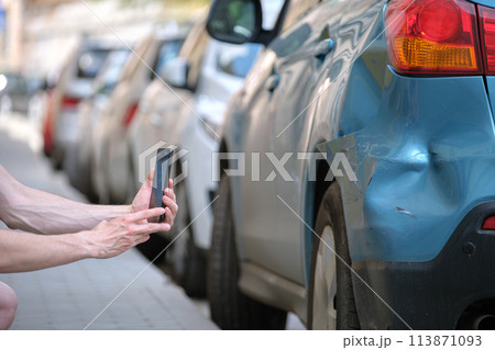 Stressed driver taking picture on sellphone camera of smashed vehicle calling for emergency service help after car accident. Road safety and insurance concept 113871093