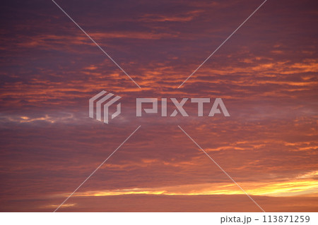 Bright colorful sunset sky with vivid smooth clouds illuminated with setting sun light spreading to horizon Bright colorful sunset sky with vivid smooth clouds illuminated with setting sun light spreading to horizon 113871259
