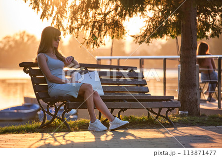 Young woman sitting on city street alone waiting for someone to arrive. Being late on date meeting concept Young woman sitting on city street alone waiting for someone to arrive. Being late on date meeting concept 113871477