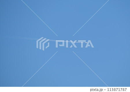 Distant passenger jet plane flying on high altitude on clear blue sky leaving white smoke trace of contrail behind. Air transportation concept 113871787