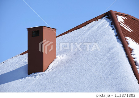 Closeup of house roof top covered with snow in cold winter. Tiled covering of building in wintertime weather Closeup of house roof top covered with snow in cold winter. Tiled covering of building in wintertime weather 113871802
