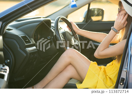 Young woman driver in yellow dress and straw hat driving a car. Summer vacation and travel concept. 113872714