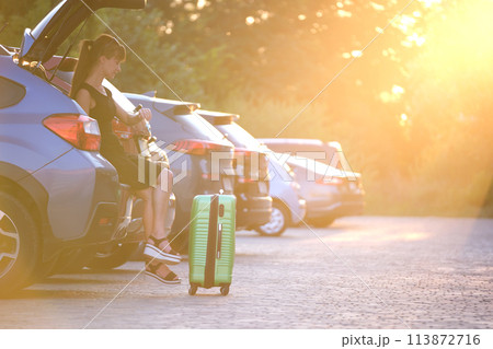 Young woman with suitcase bag waiting beside car. Travelling and vacations concept Young woman with suitcase bag waiting beside car. Travelling and vacations concept 113872716