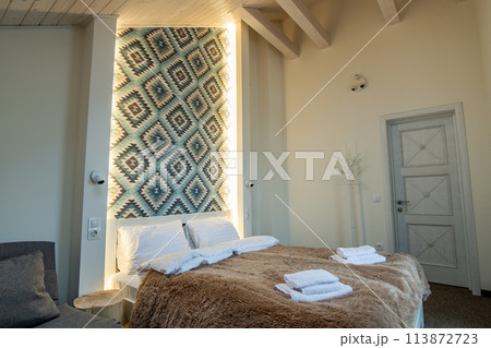 Interior of a spacious hotel bedroom with fresh linen on a big double bed. Cozy contemporary room in a modern house. 113872723