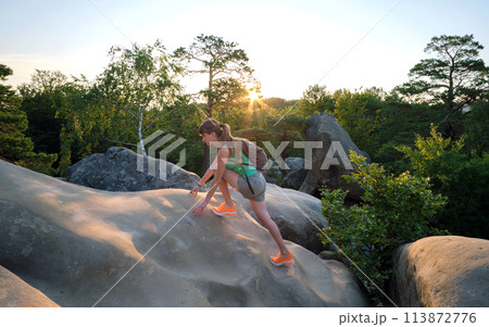 Young woman climbing alone on rocky mountain path. Female hiker enjoying difficult challenge on wilderness trail. Active way of life concept 113872776