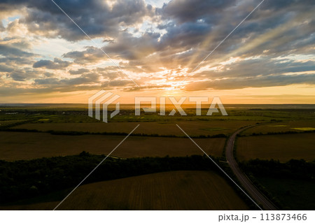 Aerial view of intercity road with fast driving cars between farmland fields at sunset. Top view from drone of highway traffic in evening 113873466
