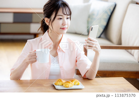 朝スマホを見る女性 113875370