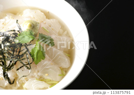 三つ葉、刻み海苔、わさびが乗った出汁入り熱々鯛茶漬けを黒背景で俯瞰撮影 113875791
