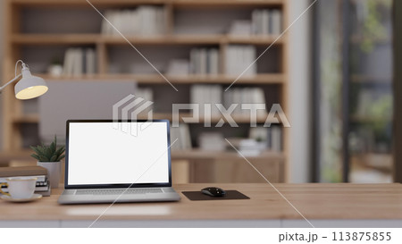 The wooden table showcases a computer in a contemporary office with a bookshelf in the background. 113875855