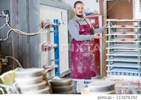 Young man posing at rack with ceramic dishes 113876292