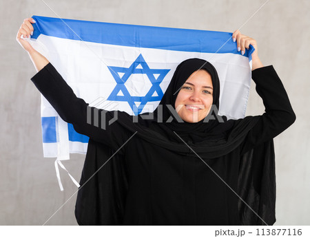 Happy young woman dressed in traditional islamic clothes with israeli flag Happy young woman dressed in traditional islamic clothes with israeli flag 113877116