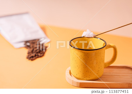 Bulletproof coffee with coconut oil. Yellow mug with a spoon of sugar and coffee beans 113877451