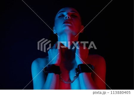 Girl in handcuffs. Beautiful young Woman in color lights Girl in handcuffs. Beautiful young Woman in color lights 113880405