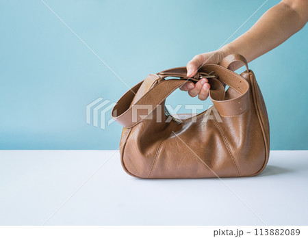 Woman holding a brown leather bag. 113882089