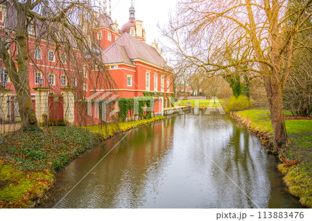 The warm hues of spring afternoon envelop Chateau Bad Muskau, reflected in the serene waters of its moat. Saxony, Germany The warm hues of spring afternoon envelop Chateau Bad Muskau, reflected in the serene waters of its moat. Saxony, Germany 113883476