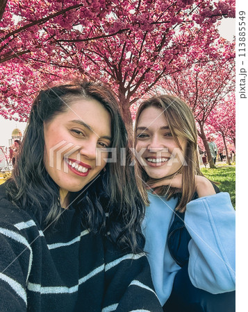 two happy girlfriends taking selfie under blooming sakura tree two happy girlfriends taking selfie under blooming sakura tree 113885549