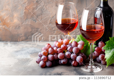 Wine bottle, glass and grapes isolated on a granite background. Rose wine splashing in glassware Wine bottle, glass and grapes isolated on a granite background. Rose wine splashing in glassware 113890712