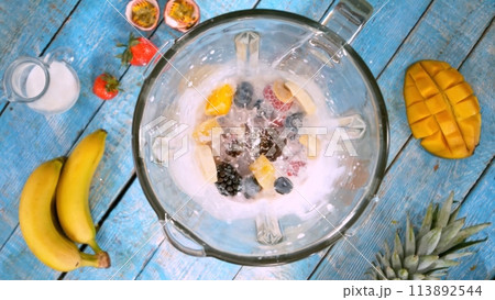 Overhead Shot of Pieces of Fruits with Milk in Blender. Overhead Shot of Pieces of Fruits with Milk in Blender. 113892544