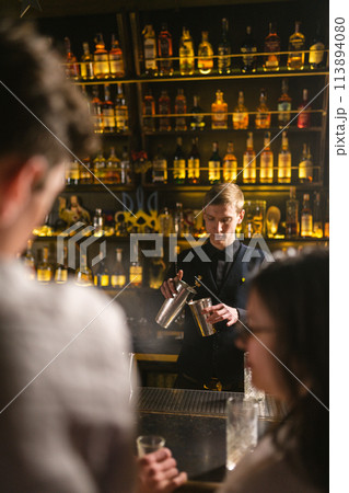 Customers sit at bar waiting for drinks from bartender Customers sit at bar waiting for drinks from bartender 113894080
