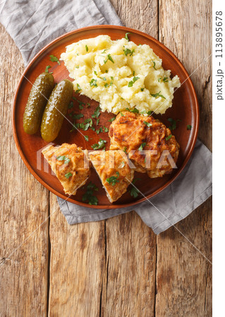 Dutch Schnitzel or Holandsky rizek in Czech, is a combination of delicious pork meat with shredded cheese, herbs served with mashed potatoes closeup on the plate. Vertical top view Dutch Schnitzel or Holandsky rizek in Czech, is a combination of delicious pork meat with shredded cheese, herbs served with mashed potatoes closeup on the plate. Vertical top view 113895678
