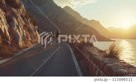 Group of cyclist ride together on road bicycles in beautiful nature. Sunset light, sea in background 113896511