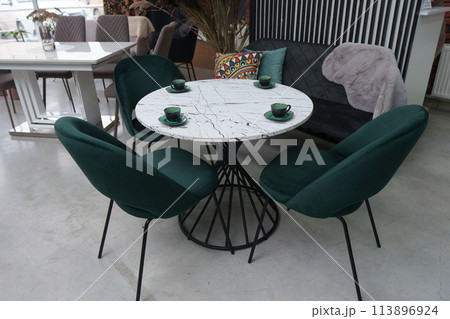 White wooden table complete with green wooden chairs with soft fabric upholstery. Green cups on the table White wooden table complete with green wooden chairs with soft fabric upholstery. Green cups on the table 113896924