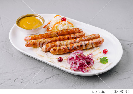 Grilled sausages with sauces and salad on plate 113898190
