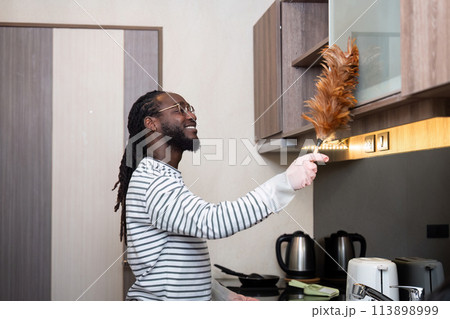 African American man young use duster cleaning in kitchen at home 113898999