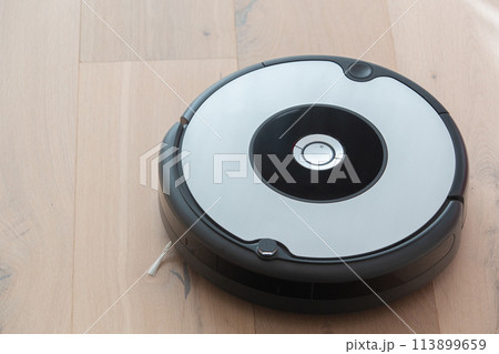 robot vacuum cleaner cleaning a wooden floor 113899659