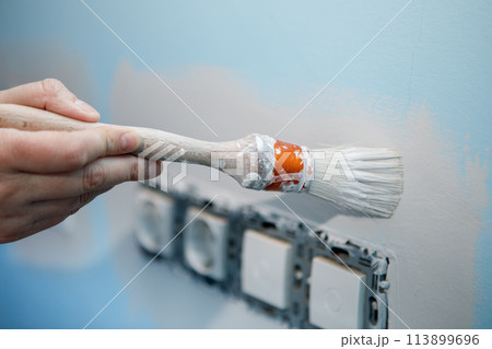 Preparation work to paint the wall of the house, edging the sockets before rolling the roller 113899696
