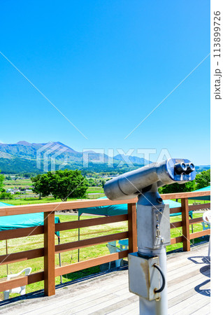 うららかな春空を背景に展望台から観える望遠鏡と阿蘇山　「道の駅 あそ望の郷くぎの」 113899726